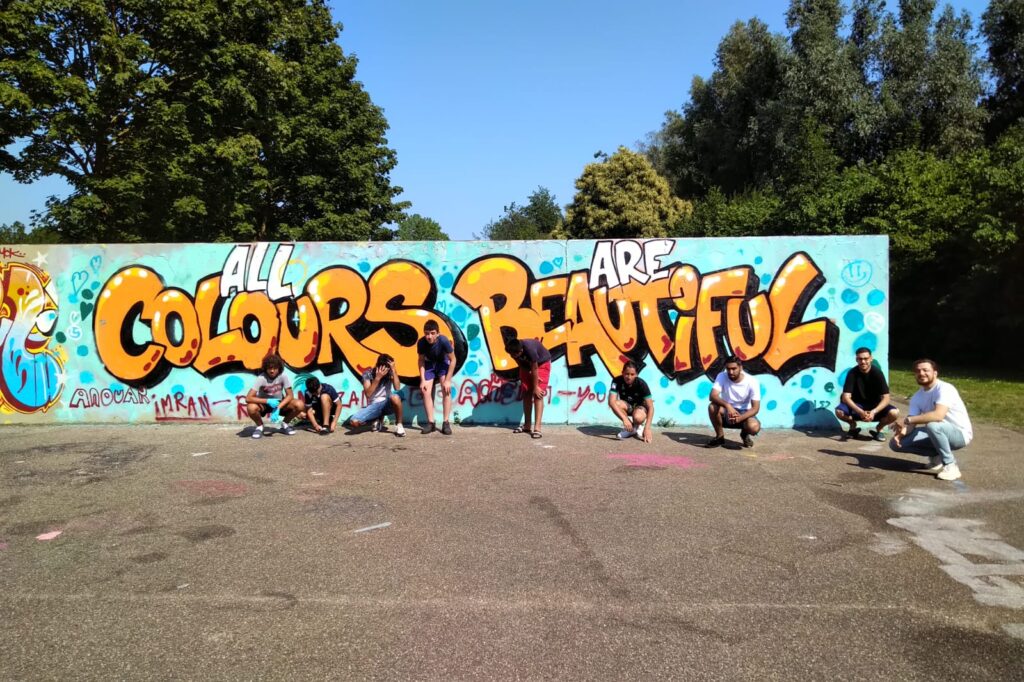 Graffitimuur gevuld met tekst 'All colours are beatiful' als reactie op eerdere tekst ACAB die op de muur stond
